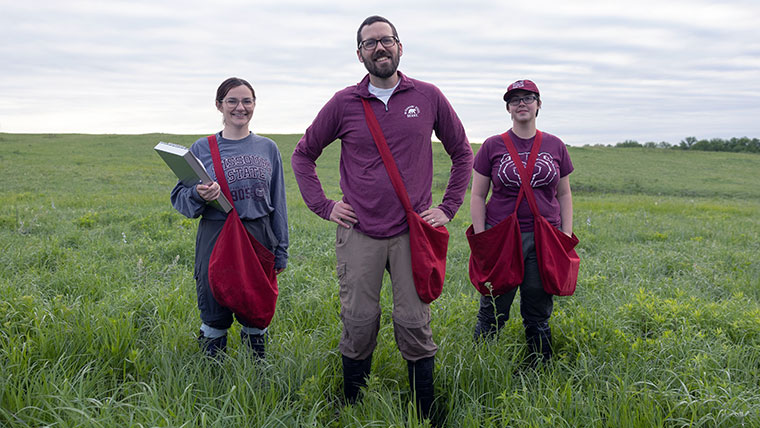 Missouri State faculty member with students standing in a green meadow.